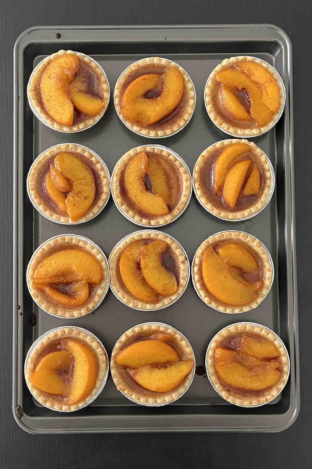 Baked peach tarts on a baking sheet.