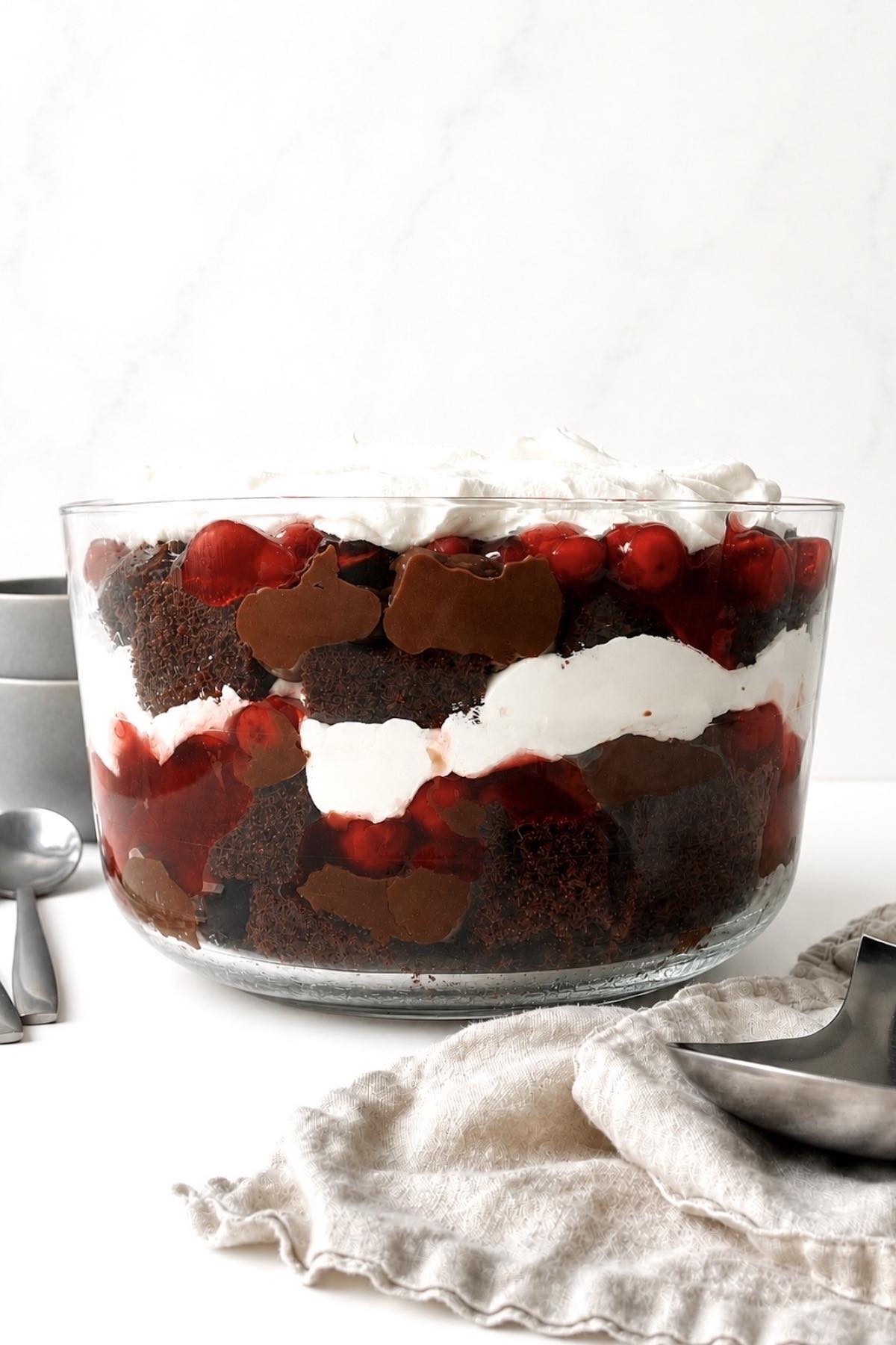 Black forest trifle in a glass trifle dish on a white table.
