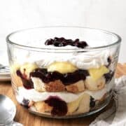 Blueberry trifle with angel food cake in a glass trifle dish on a wooden table.