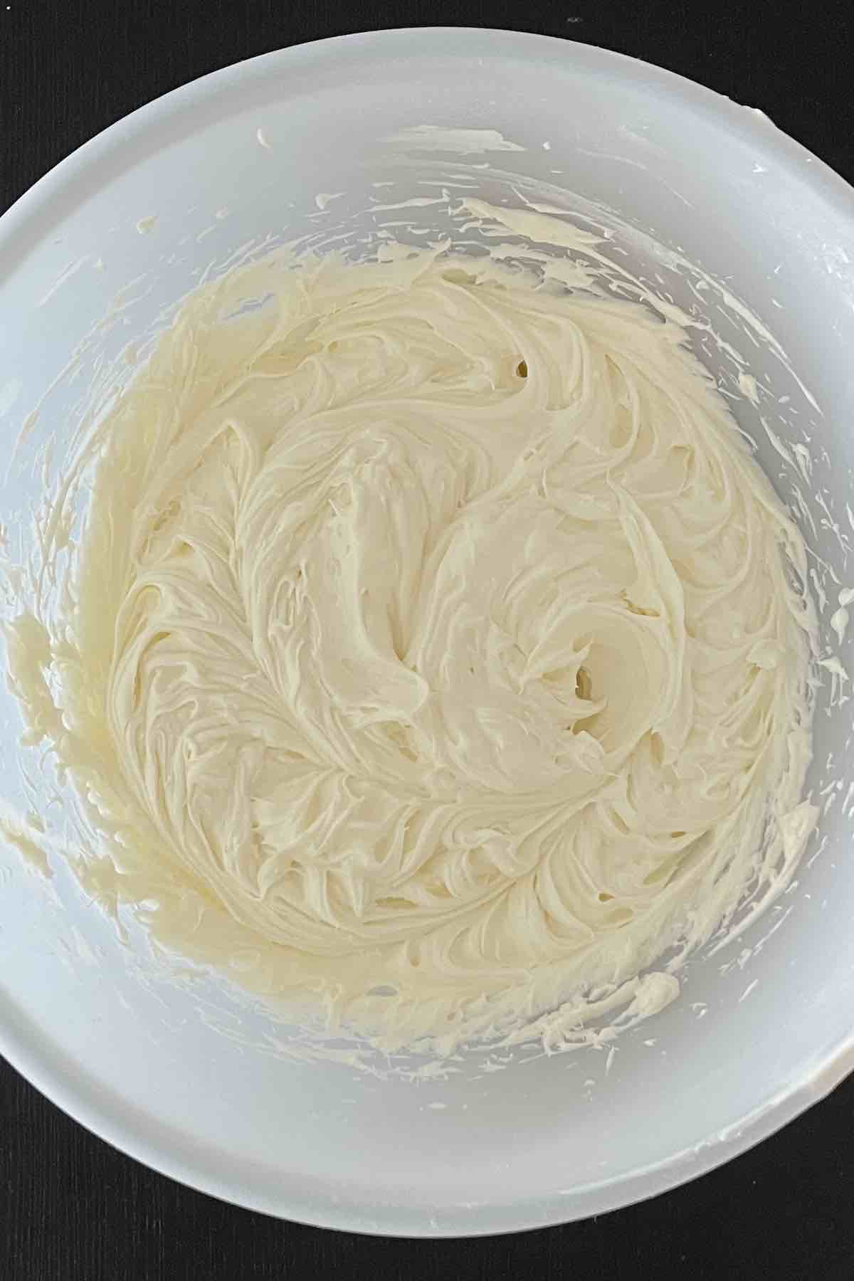 Cream cheese, sugar, and cool whip mixed together in a bowl.