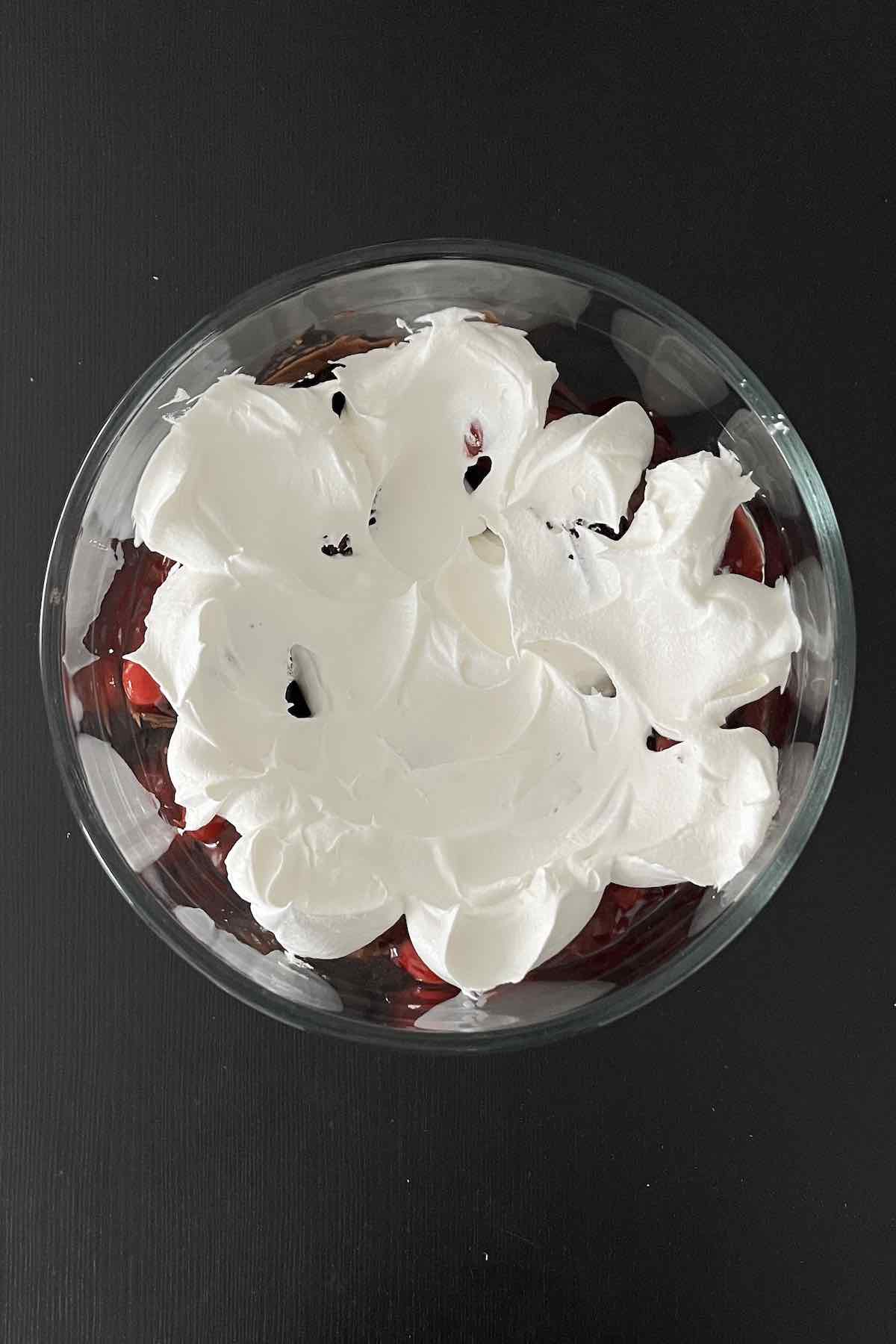 Layer of cake pieces, chocolate pudding, cherry pie filling, and Cool Whip in a trifle dish.