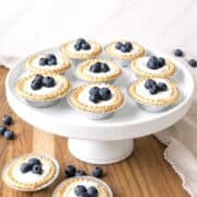 Blueberry cream cheese tarts on a white cake stand.