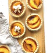 Mini peach tarts on a wooden serving board.