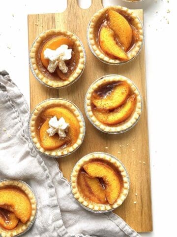 Mini peach tarts on a wooden serving board.