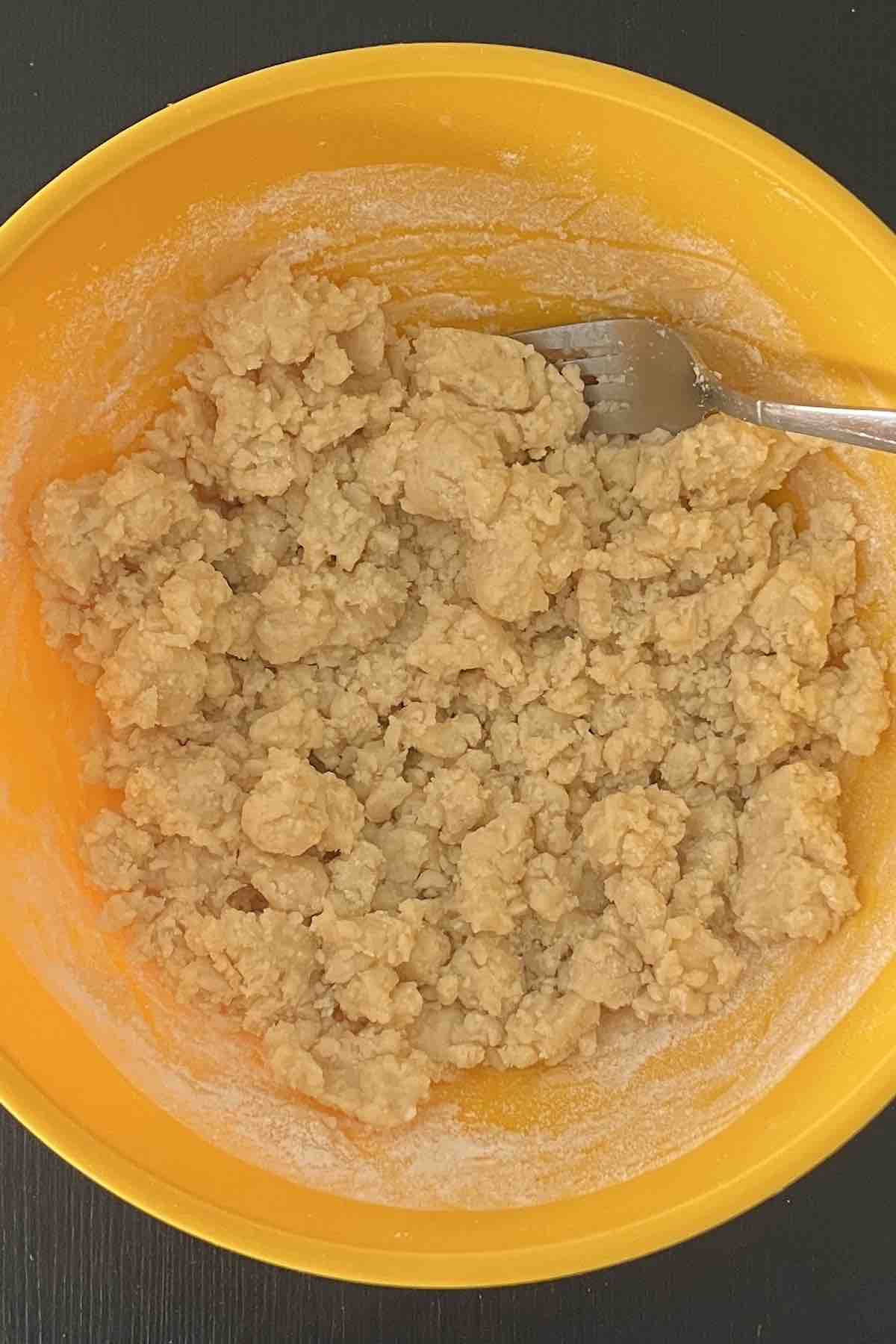 Cake mix and melted butter combined into a crumble in a bowl.