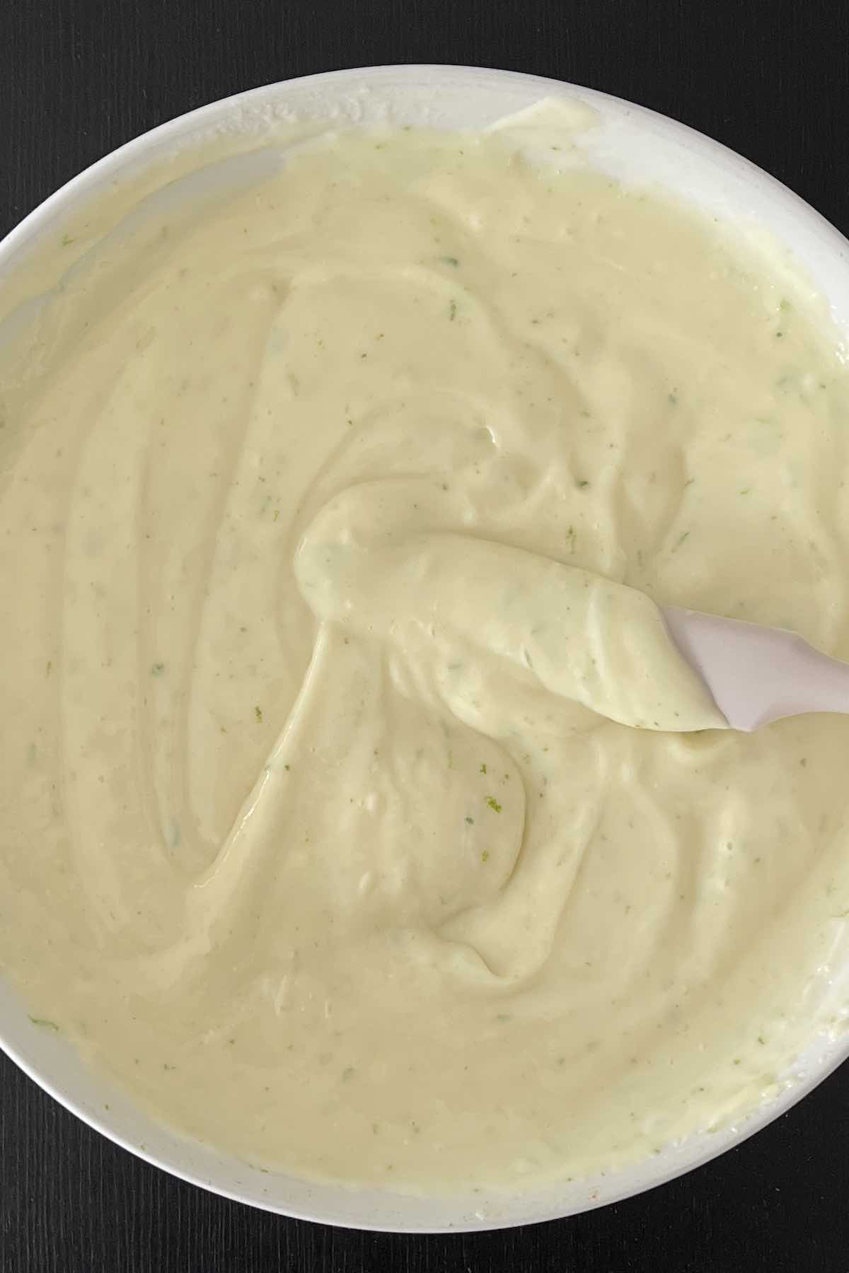 Condensed milk, lime zest and juice, and sour cream mixed together in a bowl.