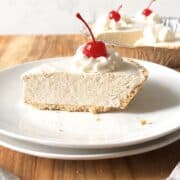 Slice of root beer float pie topped with whipped cream and a cherry on a white plate.