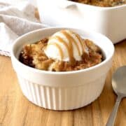 Scoop of banana dump cake in a bowl topped with vanilla ice cream and caramel sauce.