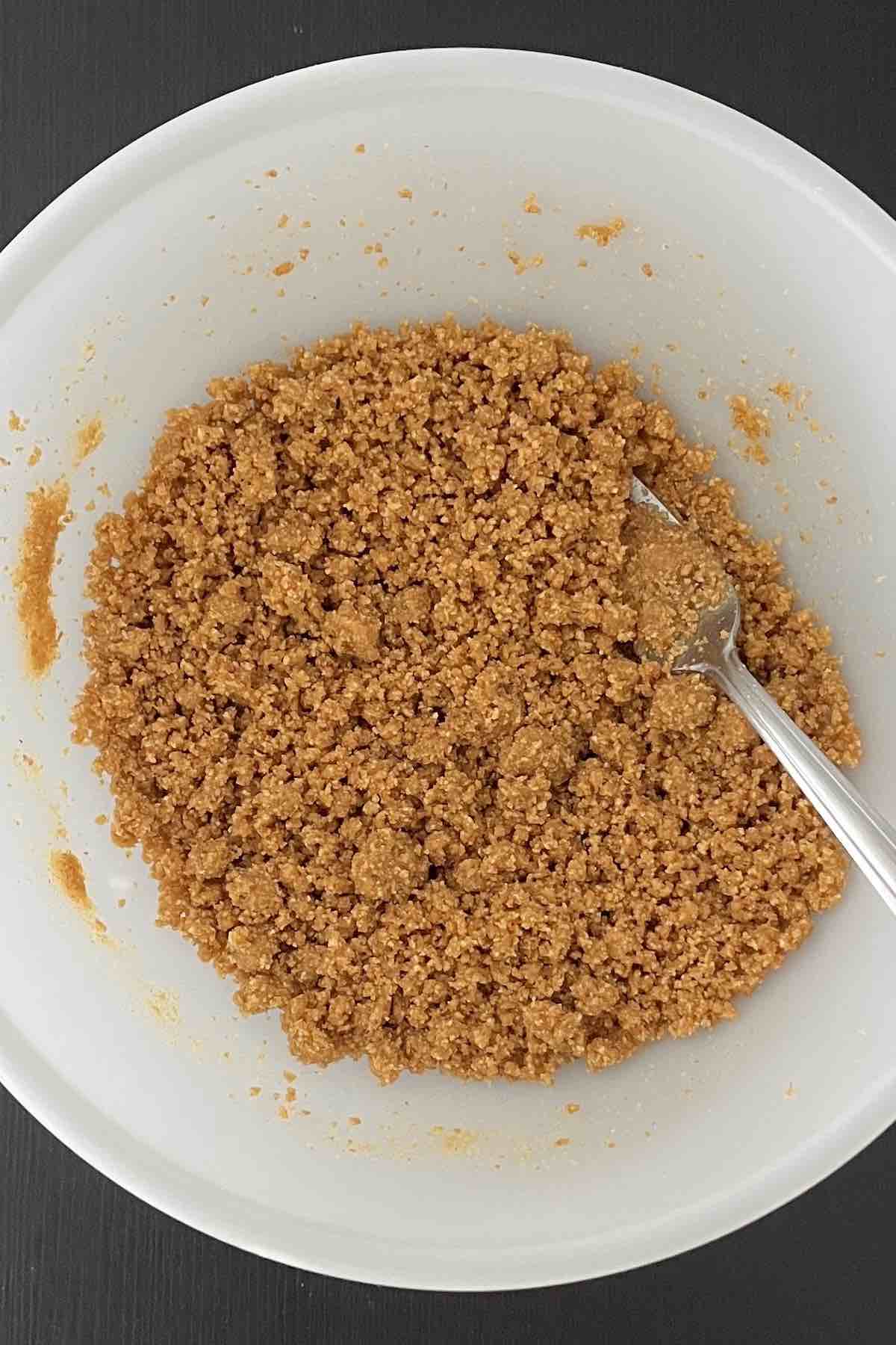 Melted butter and graham cracker crumbs in a bowl.