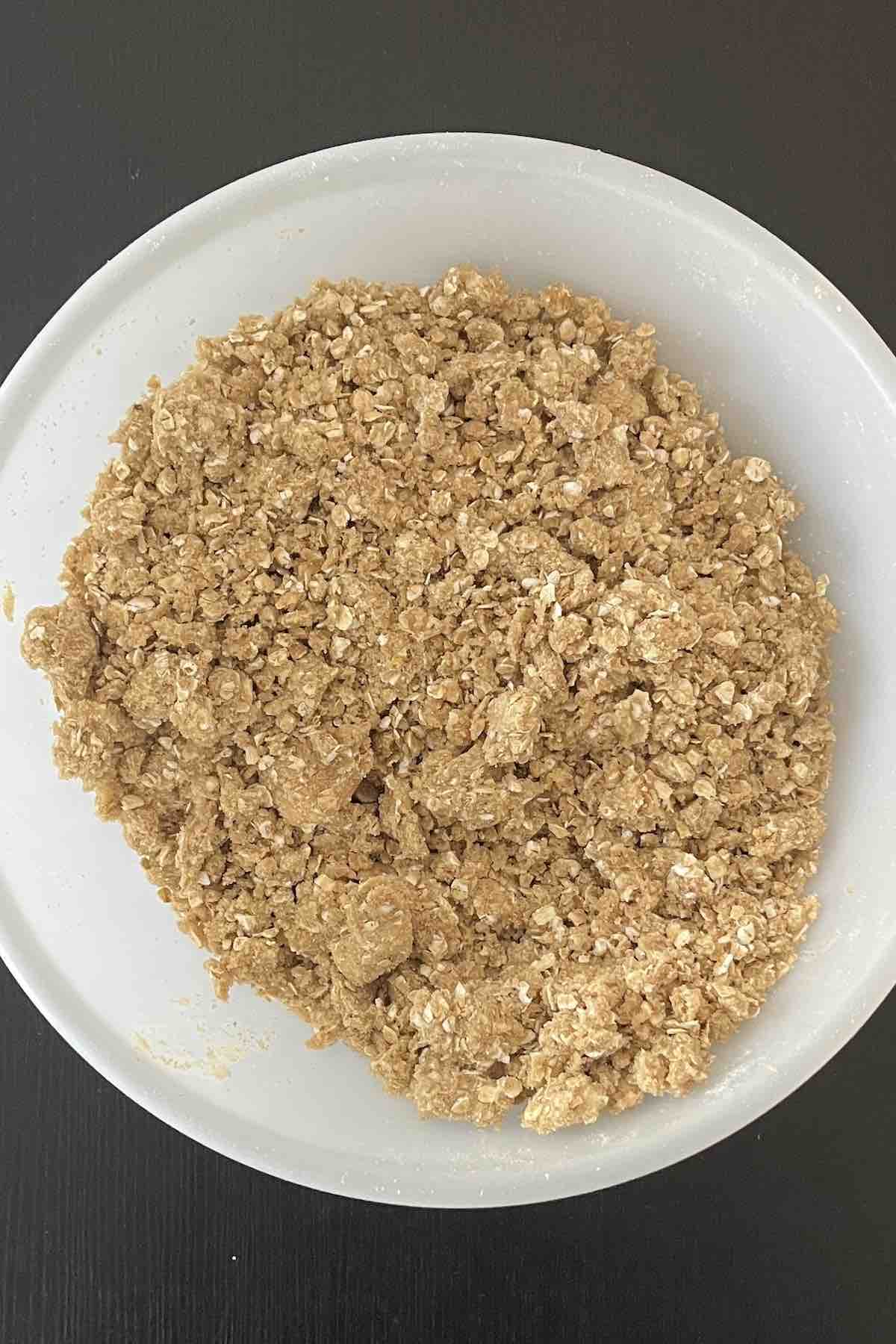 Butter added to the crisp mixture in a bowl.