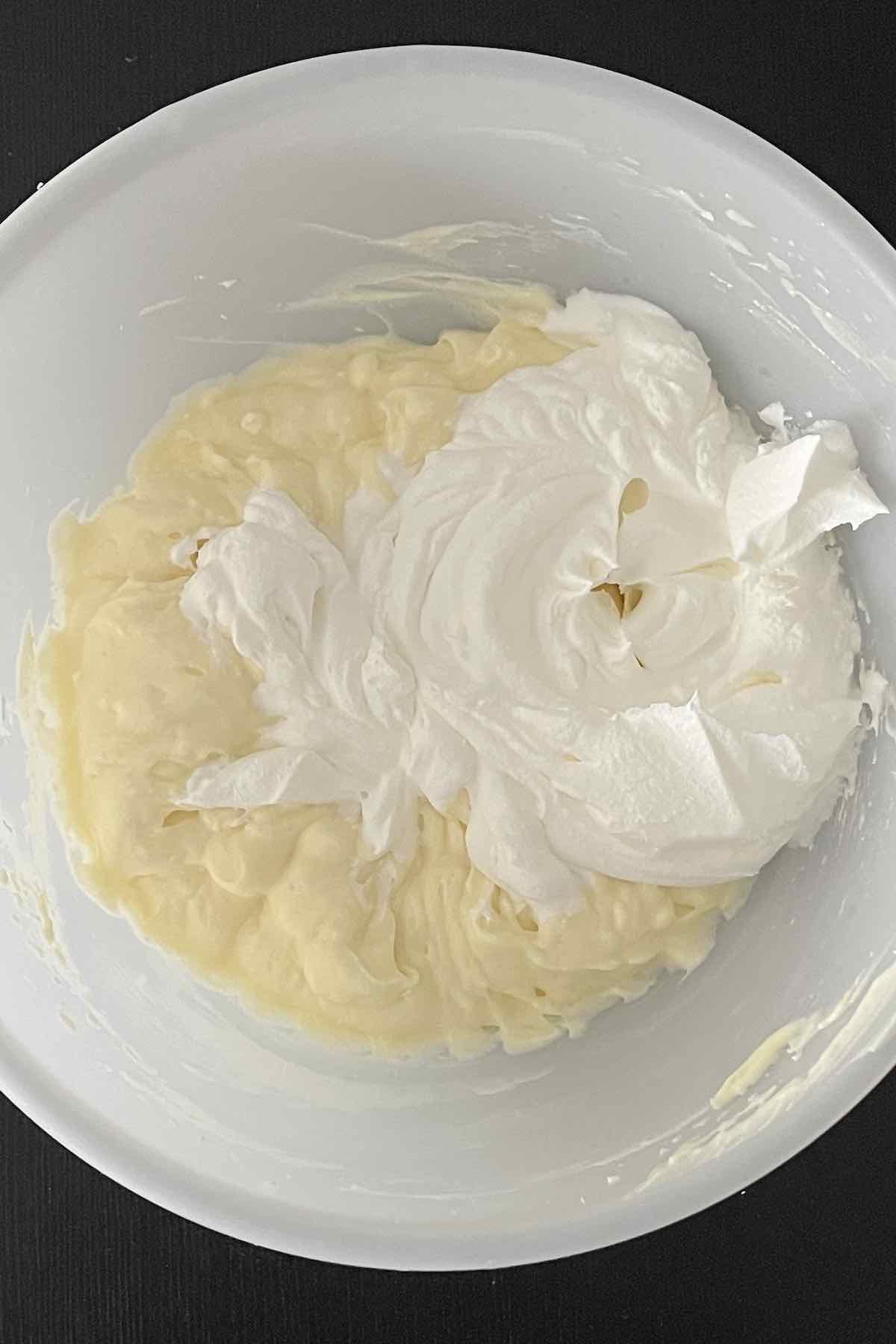 Cream cheese, vanilla pudding mix, milk, and cool whip combined in a bowl.