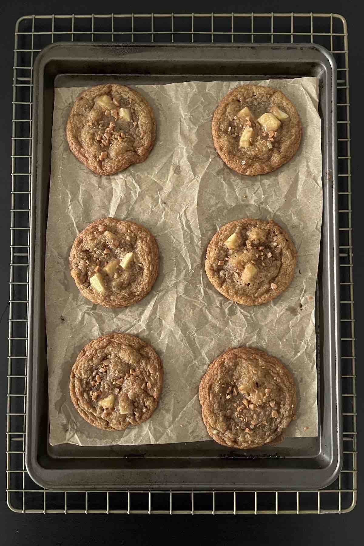 Baked caramel apple cookies on a lined baking sheet.