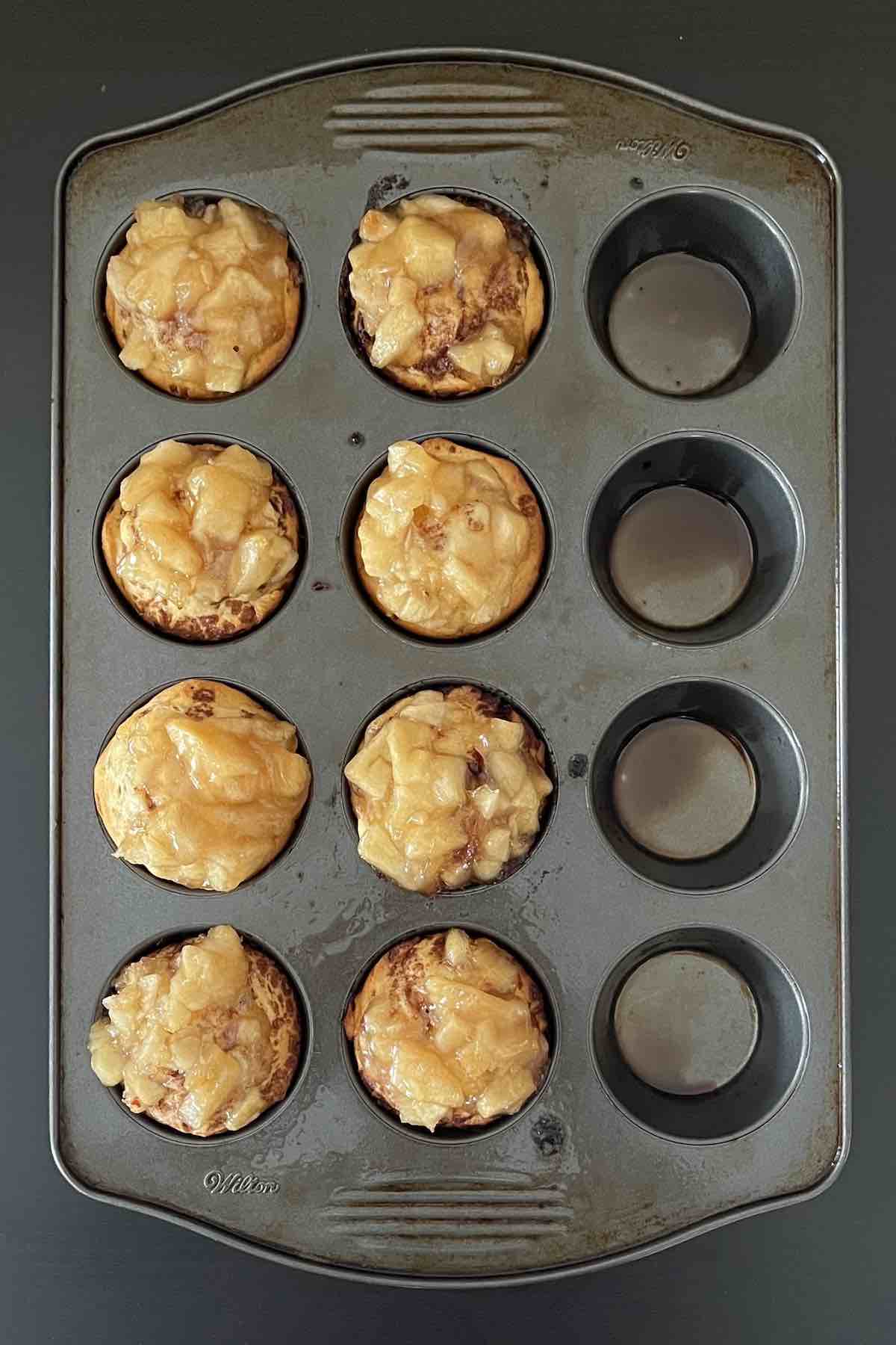 Baked cinnamon roll apple pies in a muffin pan.