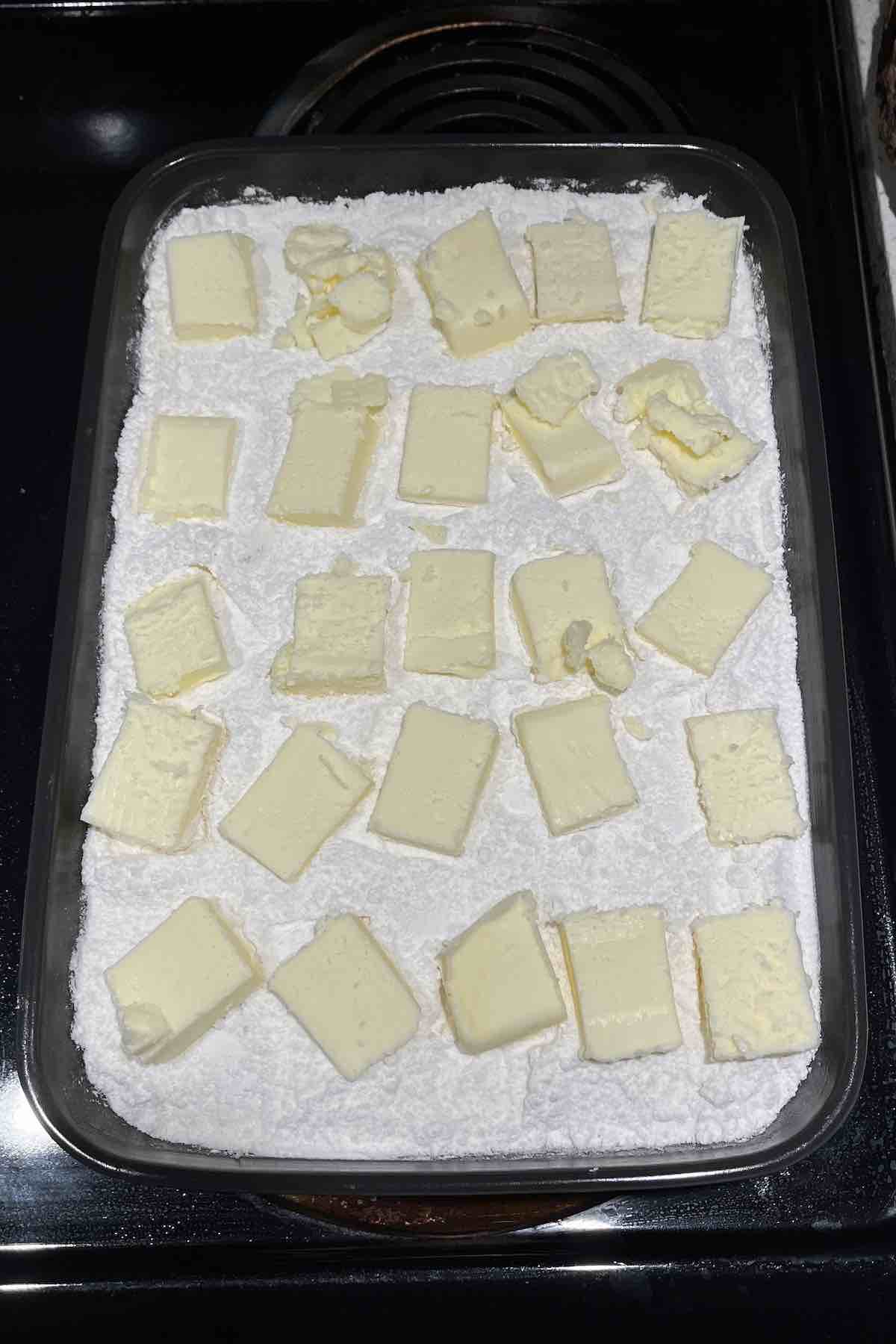 Cake mix and butter topped on the cinnamon rolls and frosting in the baking dish.