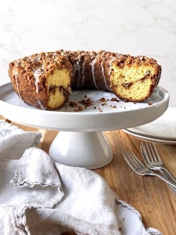 Cake mix coffee cake on a white cake stand with forks and plates in the background.