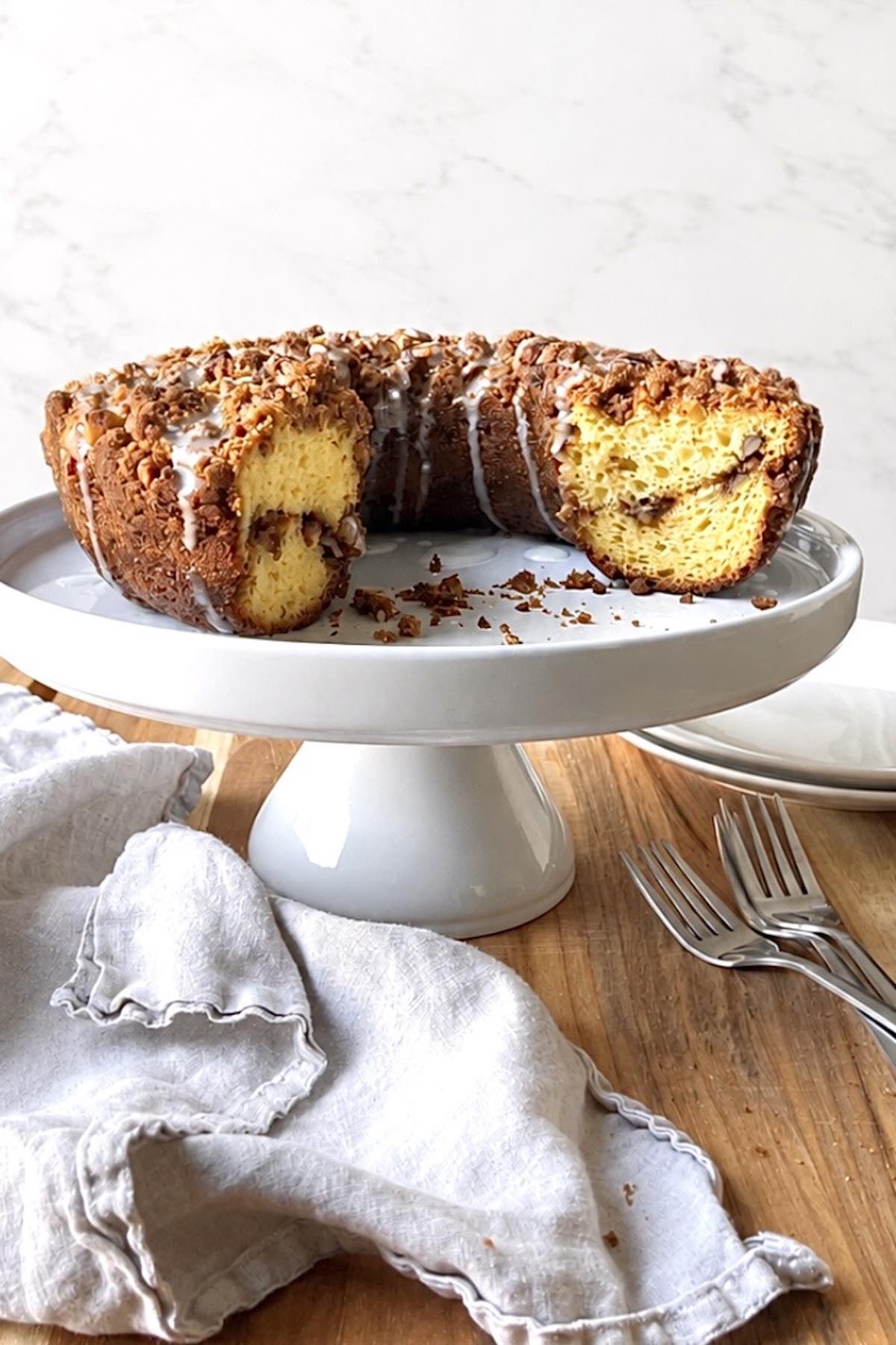 Cake mix coffee cake on a white cake stand with forks and plates in the background.