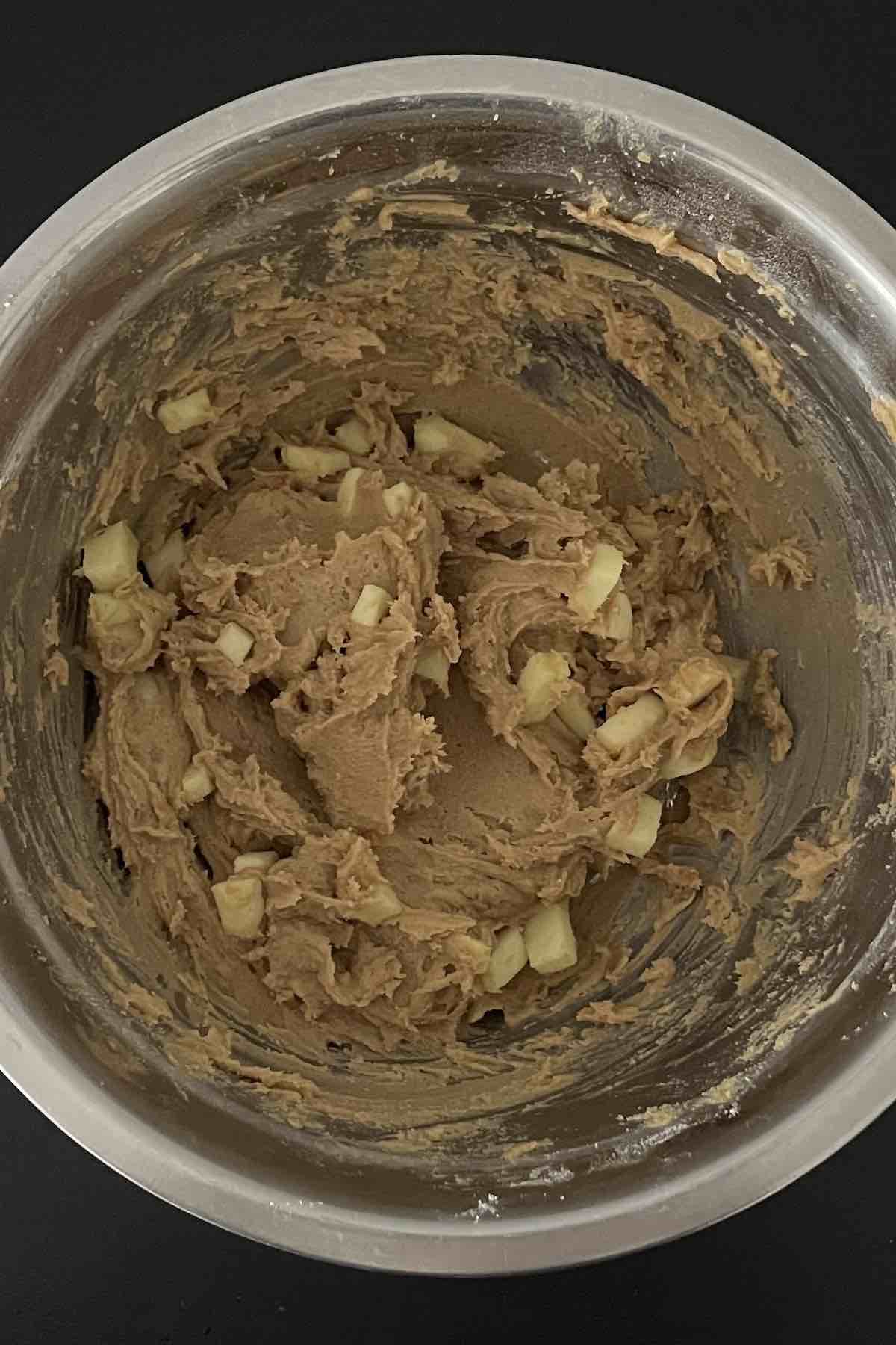 Toffee bits and diced apple folded into the bowl of cookie batter.