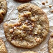 Caramel apple cookie with a bite out of it on a piece of parchment paper.