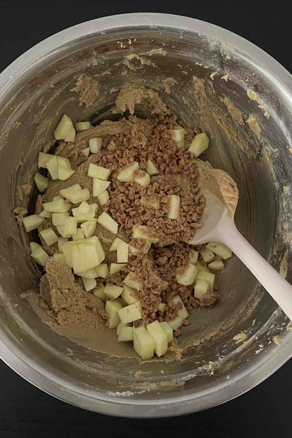 Toffee bits and diced apple added to the bowl of cookie batter.