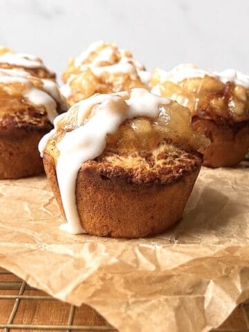 Cinnamon roll apple pies on a brown piece of parchment paper.