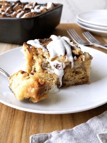 Slice of cinnamon roll dump cake on a white plate.