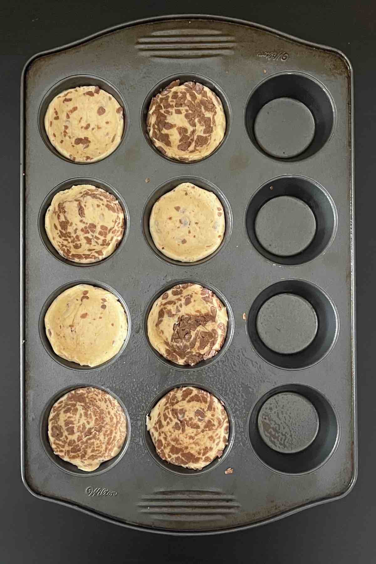 Cinnamon roll dough pressed into muffin tins.
