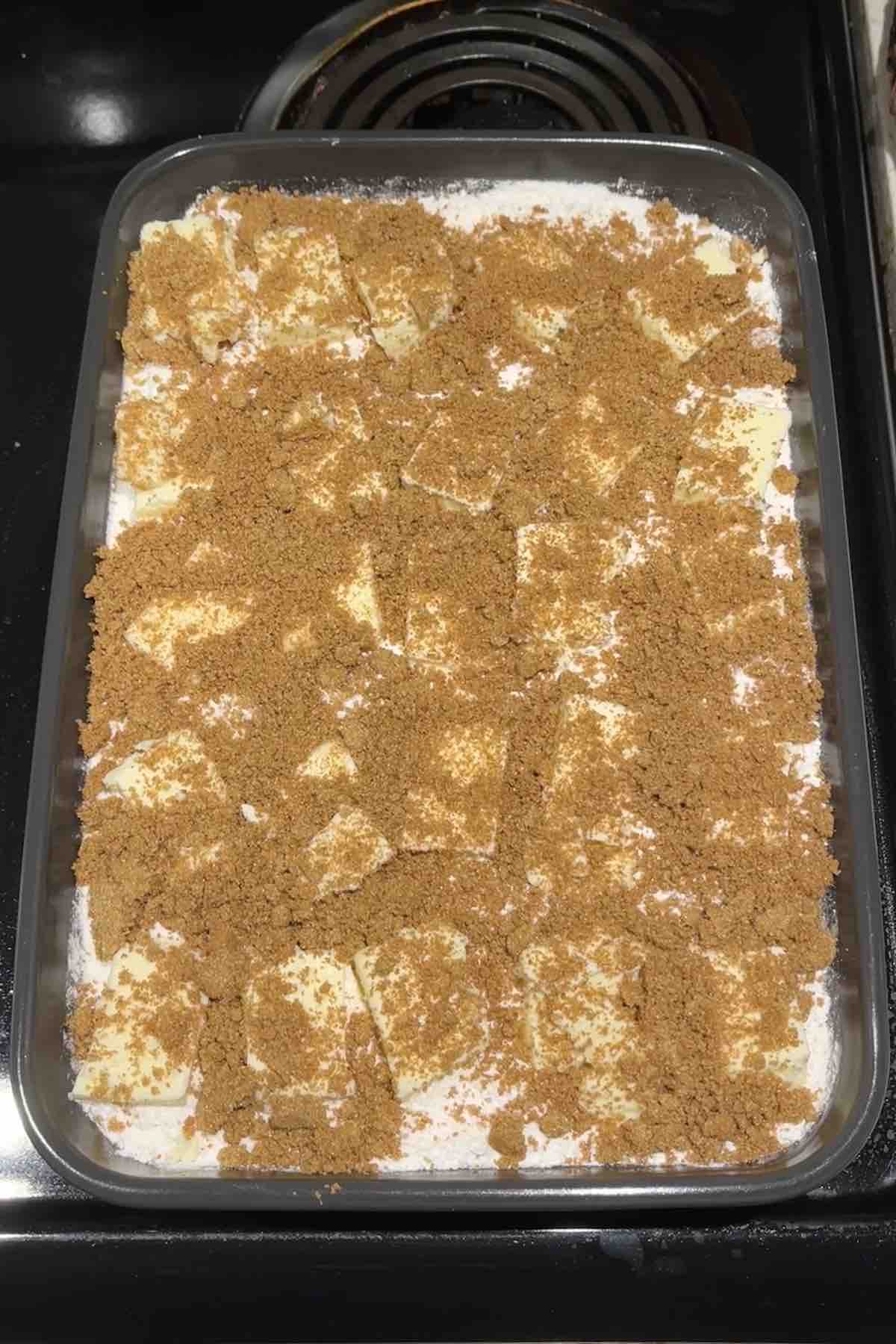 Cinnamon sugar sprinkled on top of the butter slices in the baking dish.