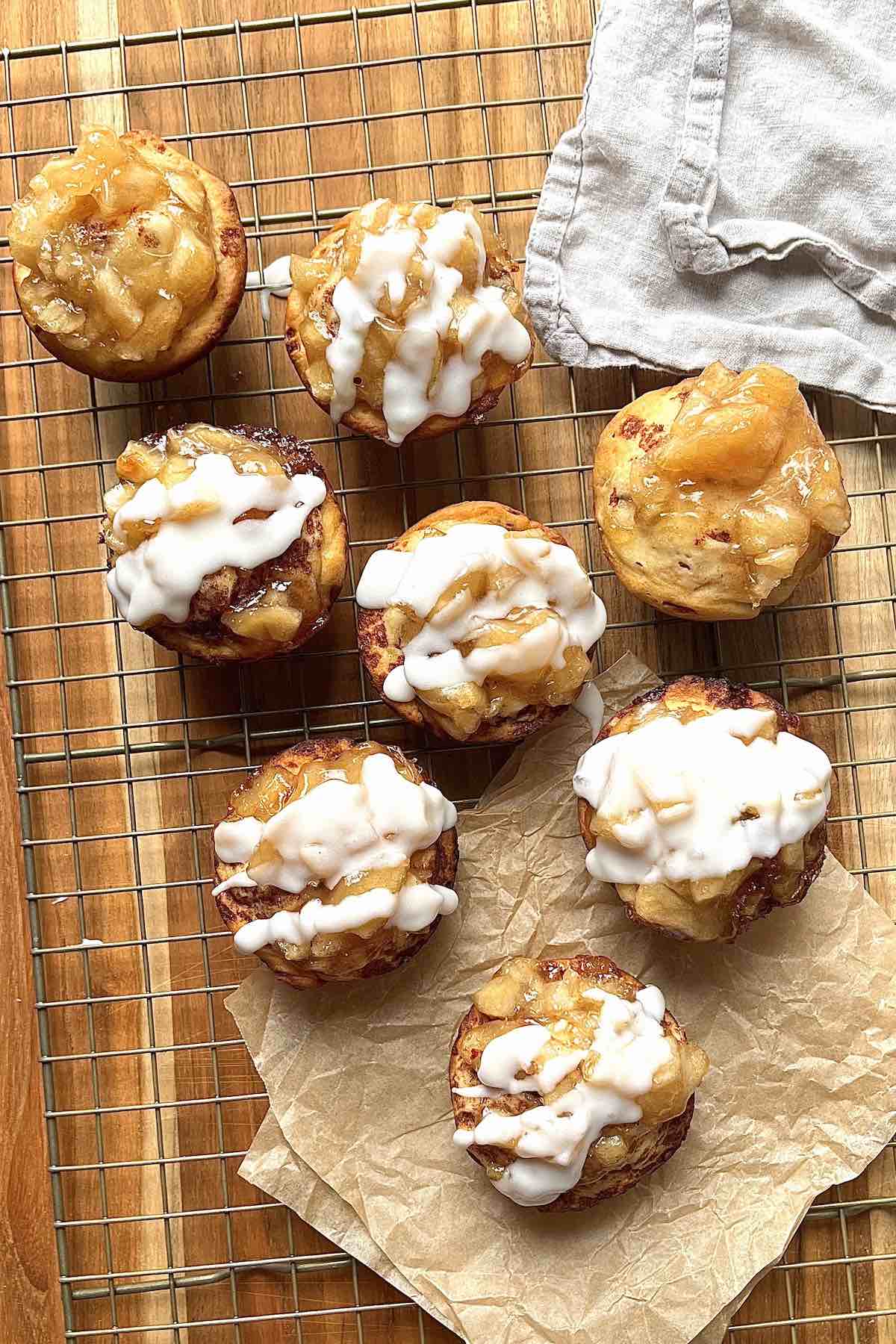Iced cinnamon roll apple pies on a cooling rack.