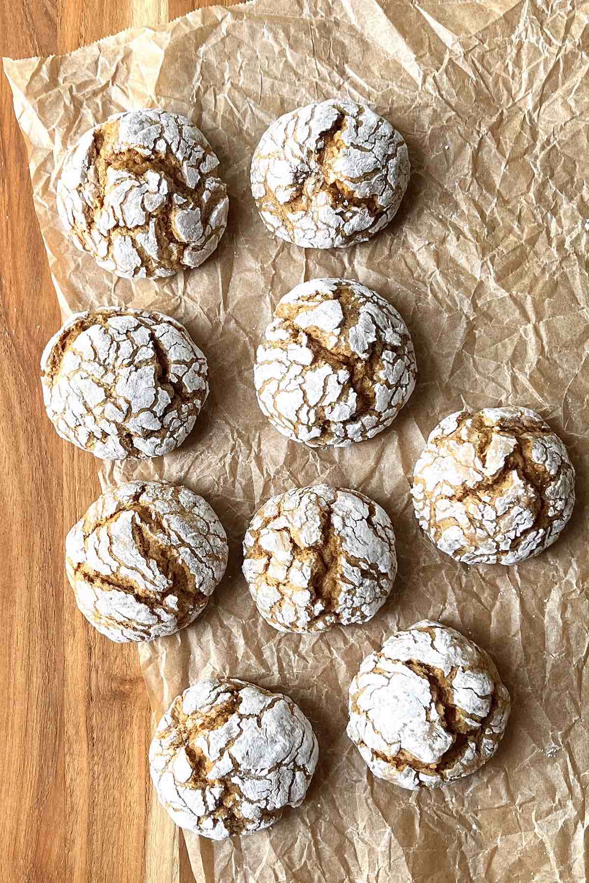 Pumpkin crinkle cookies on a wooden table on top of brown parchment paper.