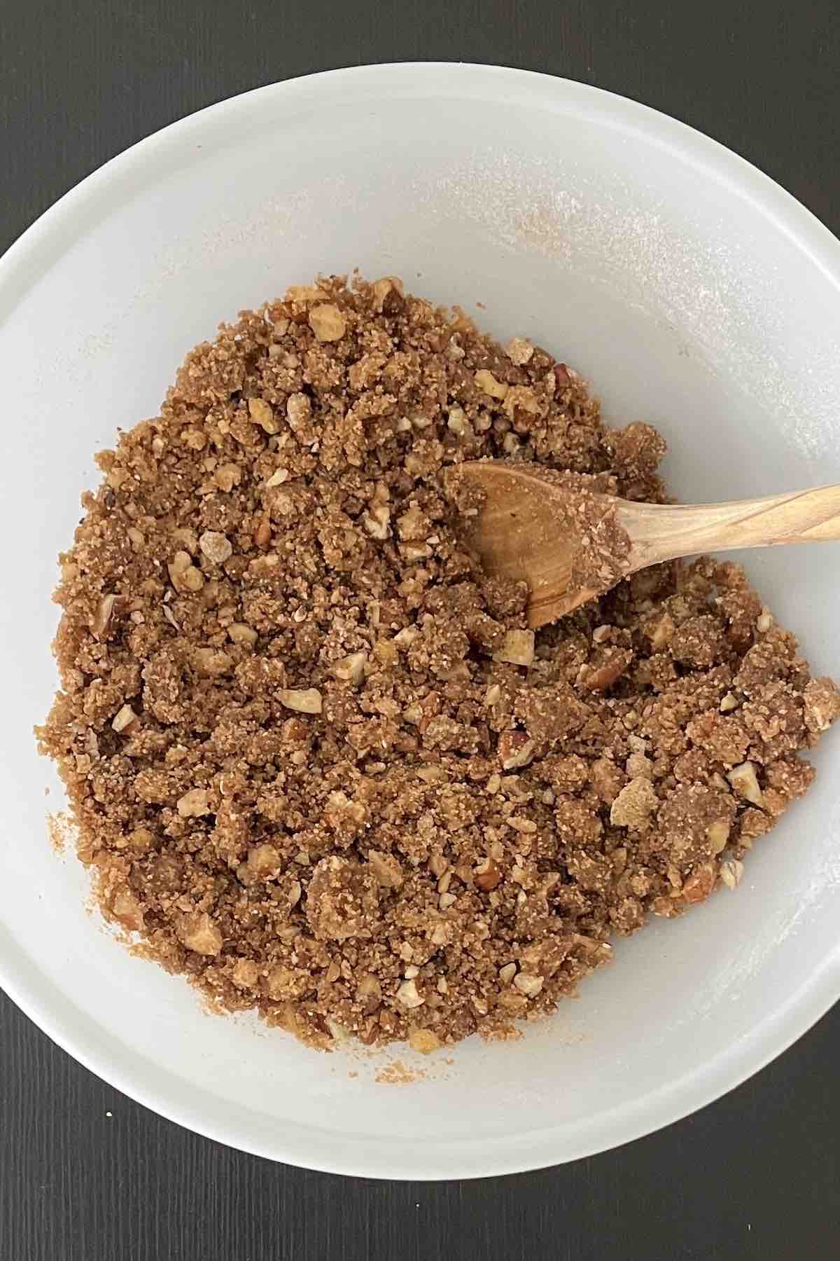 Cake mix, brown sugar, nuts, and butter mixed into a crumble in a bowl.