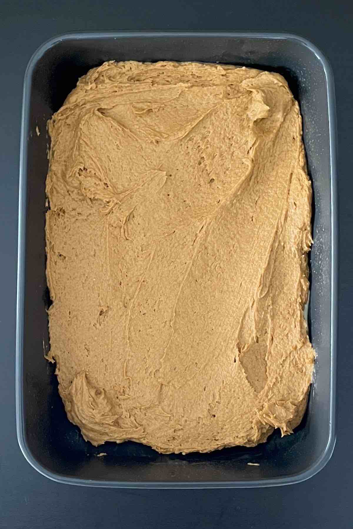 Pumpkin cake batter spread in a baking dish.