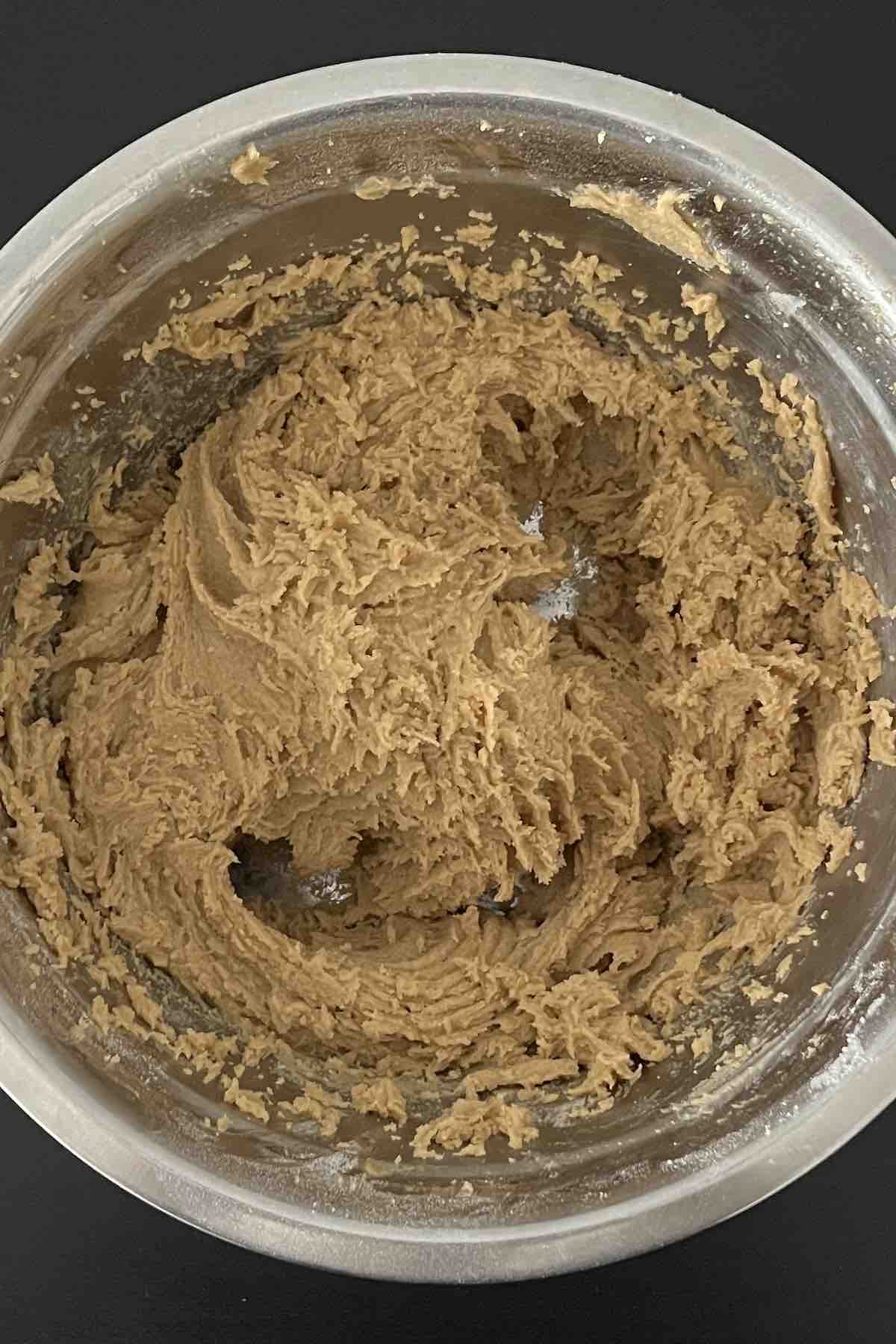 Butter, sugar, eggs, flour, baking soda, and salt mixed in a bowl.