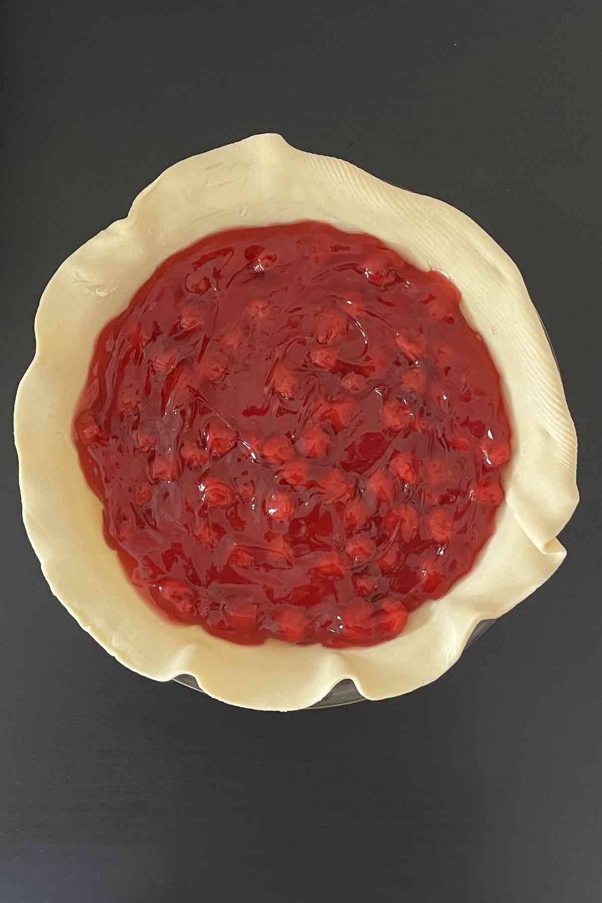 Cherry pie filling poured into pie shell.