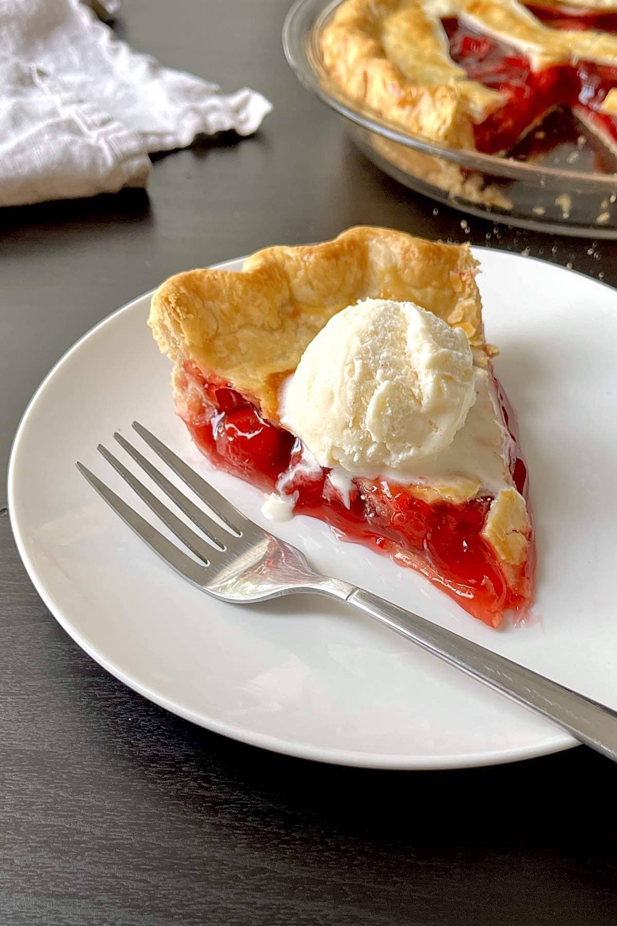 Slice of halloween pie on a white plate topped with a scoop of vanilla ice cream.