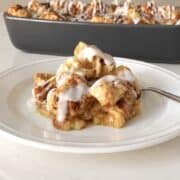 Scoop of apple cinnamon roll cake on a white plate.