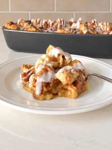Scoop of apple cinnamon roll cake on a white plate.