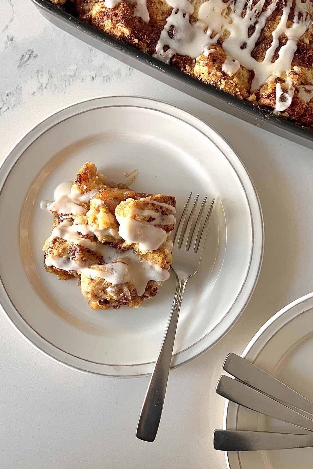 Scoop of apple cinnamon roll cake on a white plate.