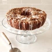 Iced apple pie filling cake on a glass cake tray.