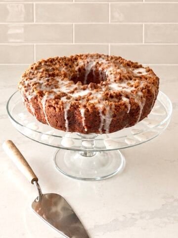 Iced apple pie filling cake on a glass cake tray.
