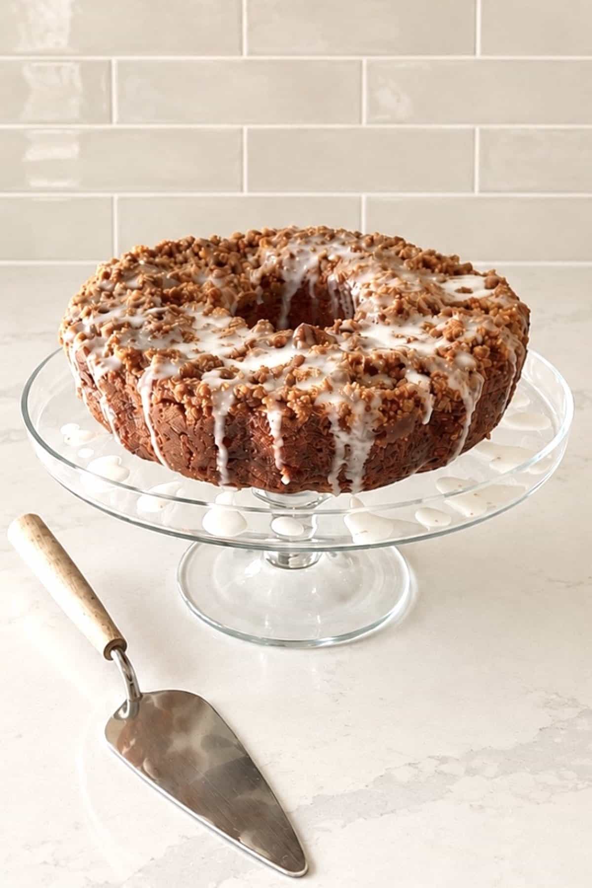 Iced apple pie filling cake on a glass cake tray.
