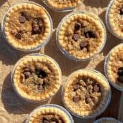 Chocolate pecan butter tarts lined on a baking sheet with brown parchment paper.