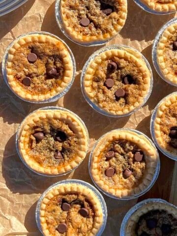 Chocolate pecan butter tarts lined on a baking sheet with brown parchment paper.