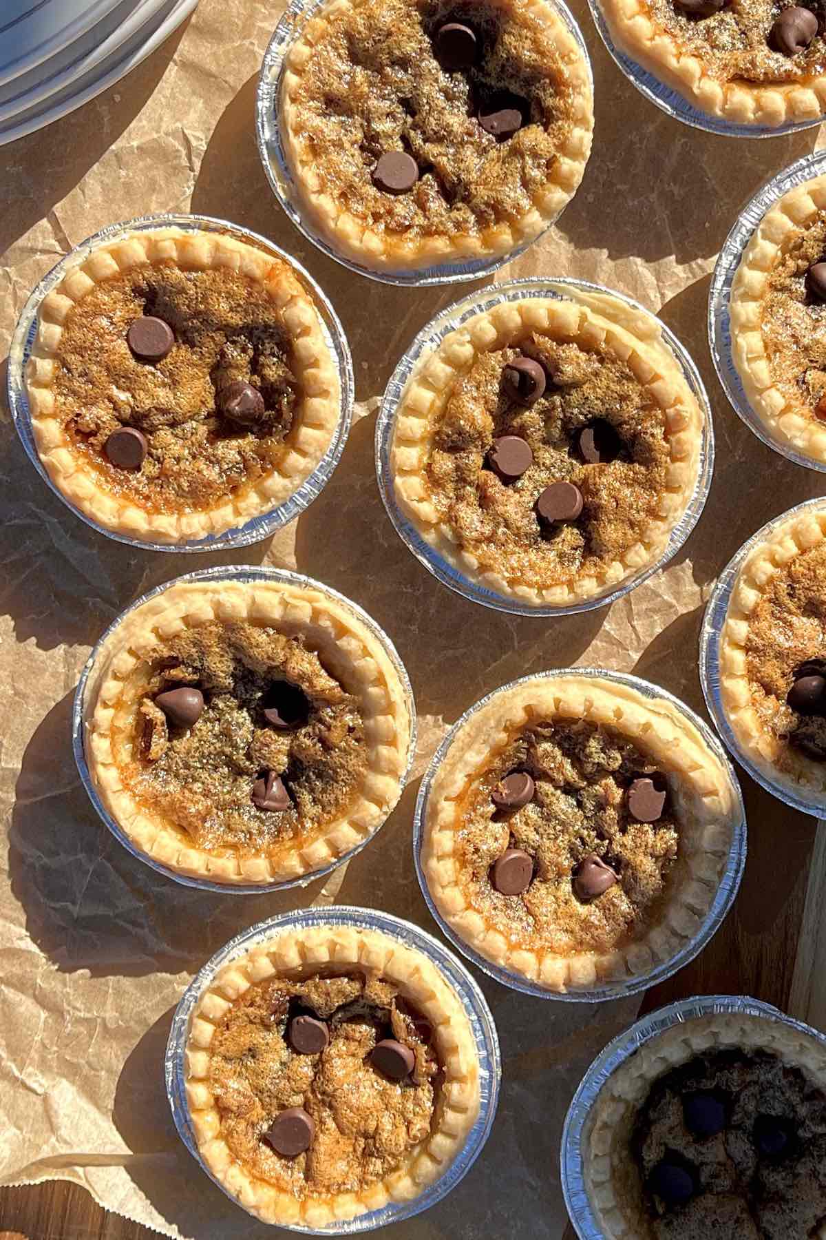 Chocolate pecan butter tarts lined on a baking sheet with brown parchment paper.