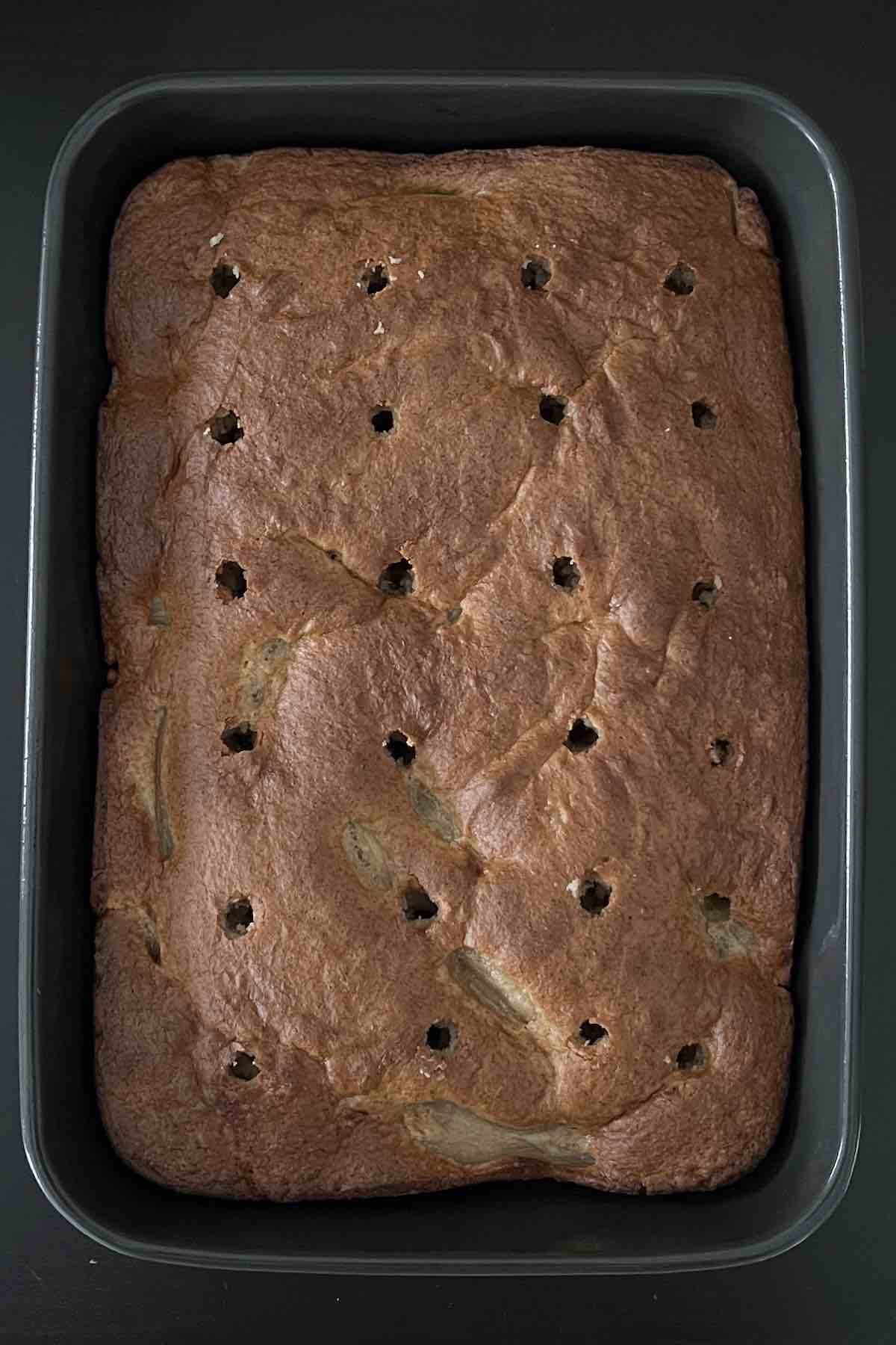 Holes poked into apple poke cake.